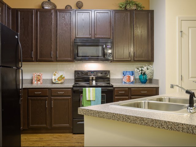 Designer countertops, custom 42" espresso finish cabinets and fresh black appliances at Coppermill Park